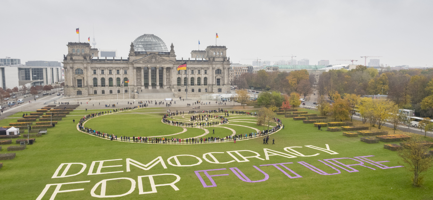 In einer Kunstaktion stehen Menschen auf einer Fibonacci-Folge auf der Wiese vor dem Reichstagsgebäude in Berlin